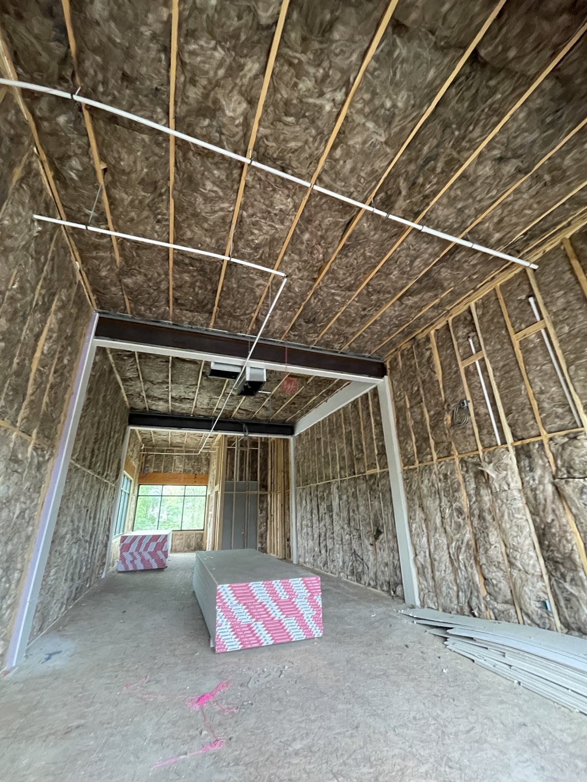 Fiberglass batt insulation installed throughout a long new construction room