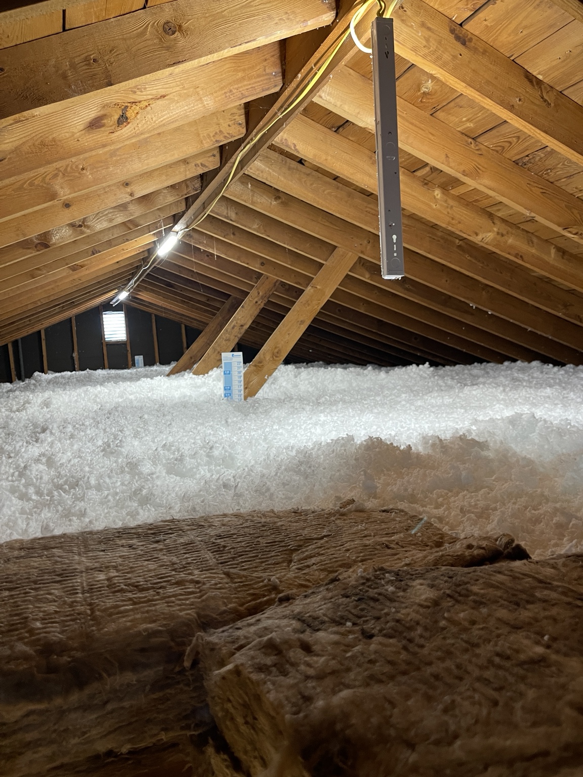 Deep, even layer of white blown-in insulation across an attic floor